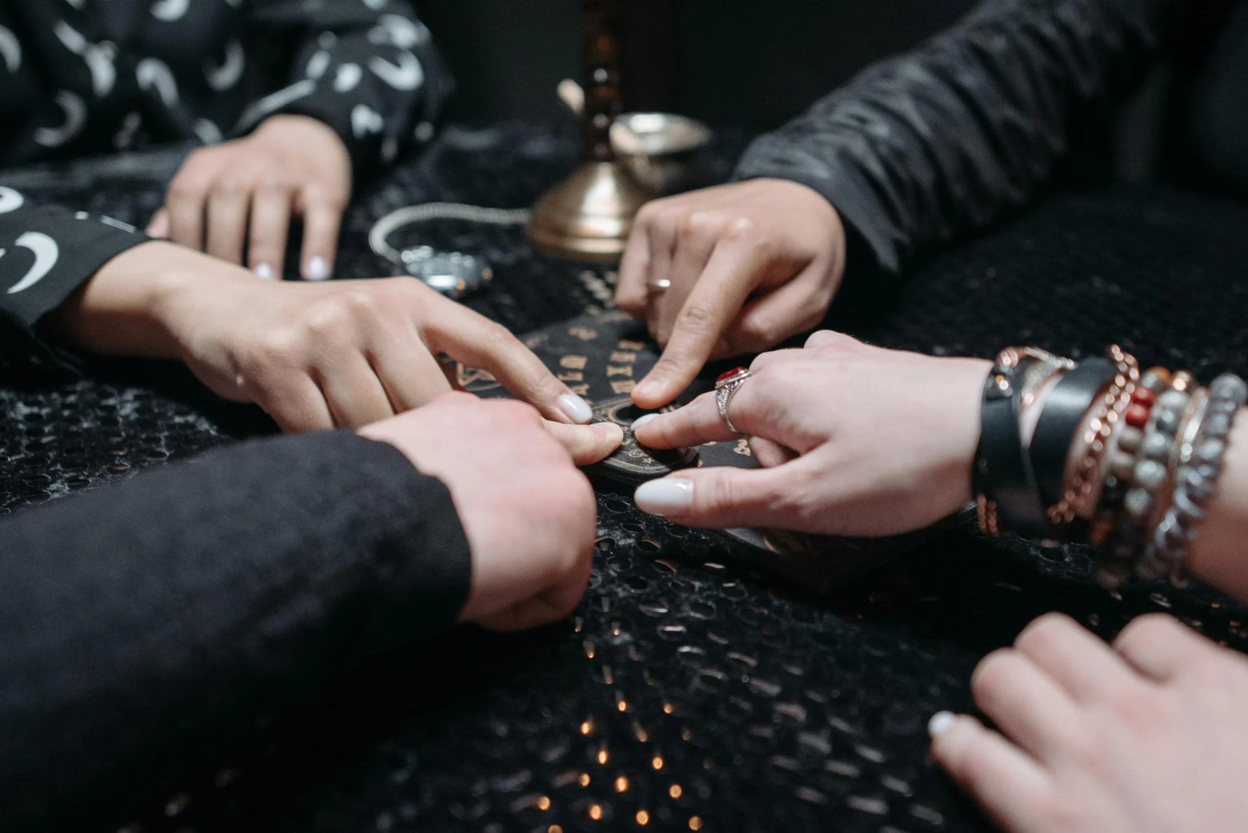 Hands on a Ouija board planchette during a seance, representing practices associated with seeking unseen knowledge, contrasted with Islamic teachings. Tarot Readings For Spiritual Awakening - tarot readings for spiritual awakening